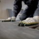 Close-up view of workers gloved hands installing flooring system